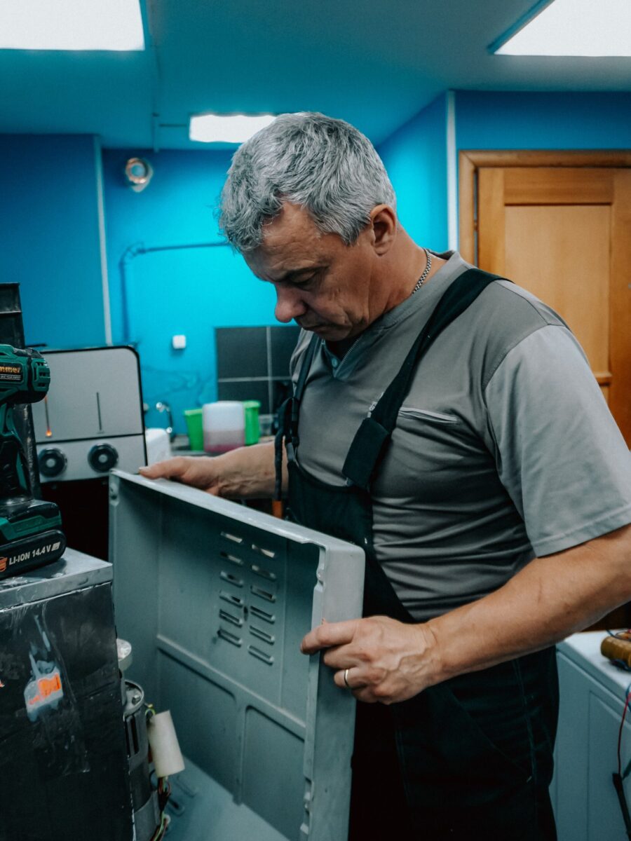 Repair technician examines appliance indoors, showcasing focus and skill.